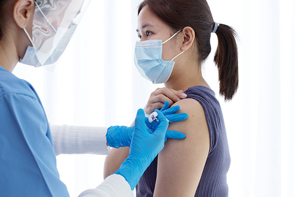 A nurse giving a vaccination into a patient’s upper arm